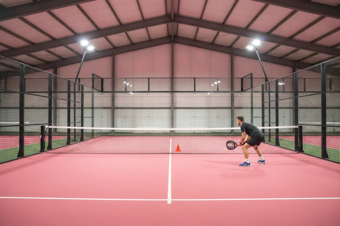 Joueur de padel travaillant son amortie à l'entraînement, terrain indoor rose