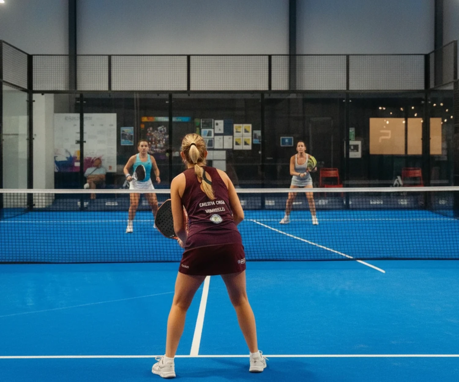 Joueurs de padel actifs et souriants en plein match, terrain indoor bleu