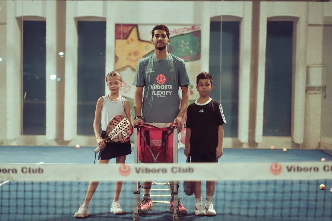 Coach de padel encadrant deux joueurs sur le court