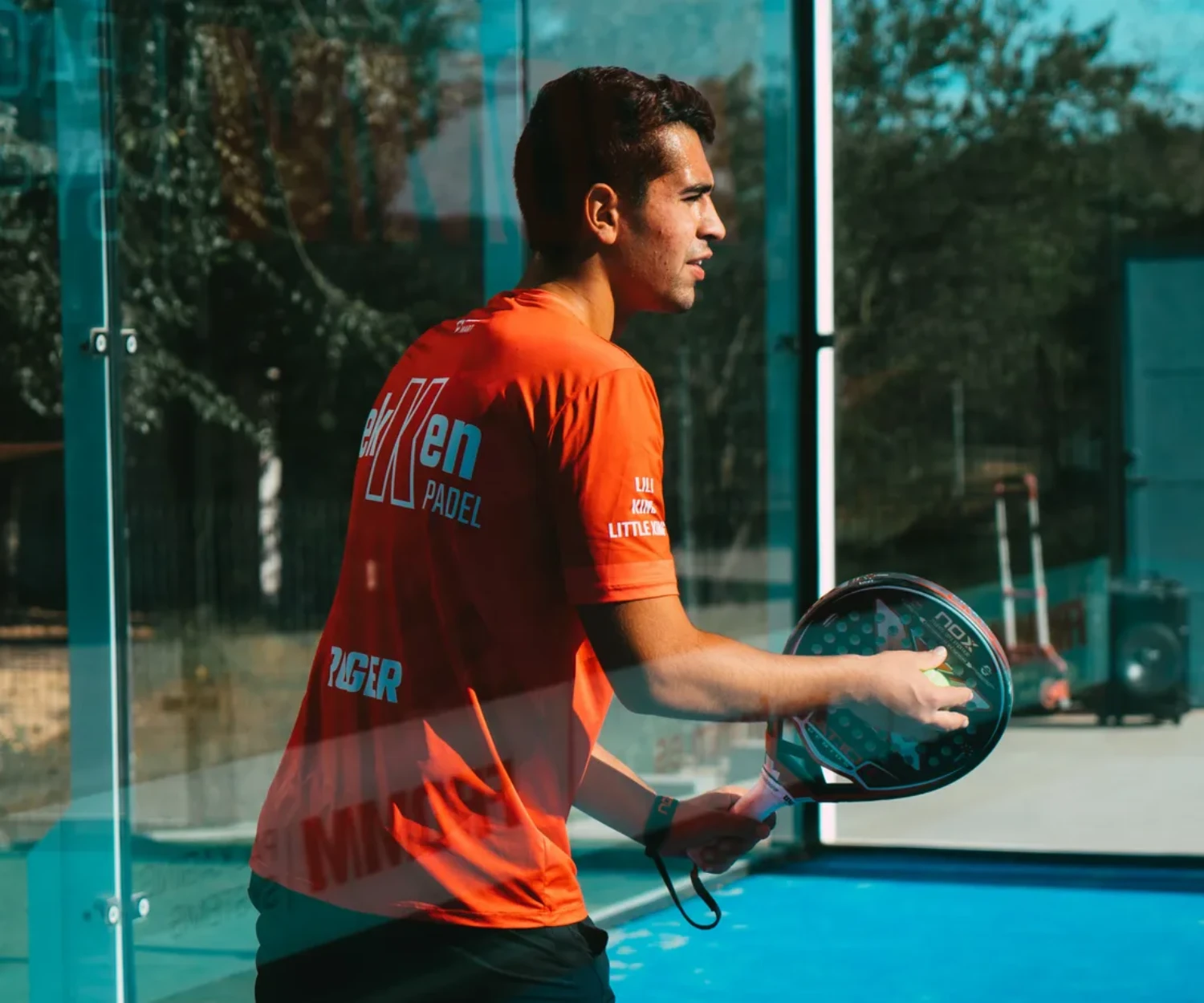 Joueur a l'entrainement avec un coach de padel sur un court exterieur