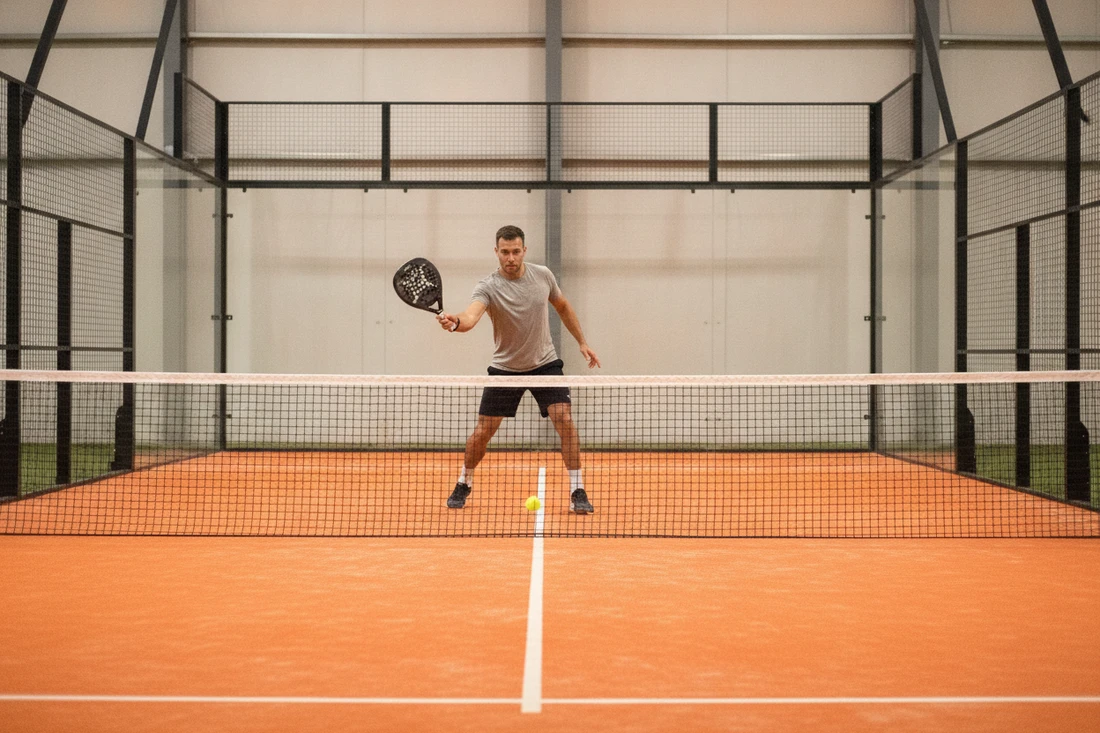 Joueur de padel servant bas et croise puis montant au filet