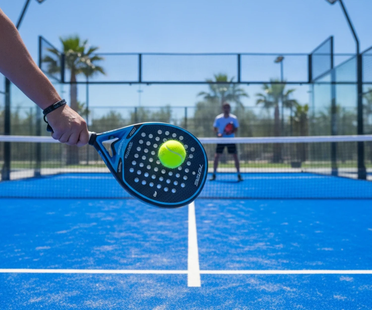 Balle de padel rapide ou lente posée sur une raquette pleine sur un court vitré