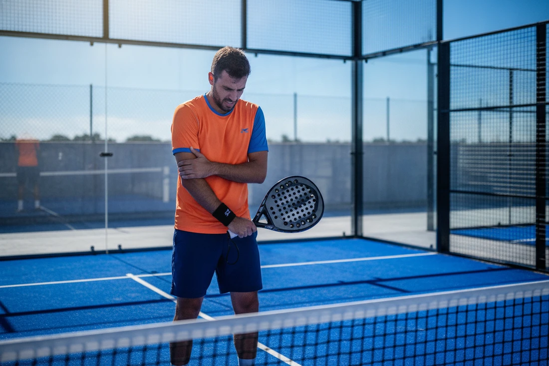Symptômes du tennis elbow au padel, joueur grimaçant en tenant son coude