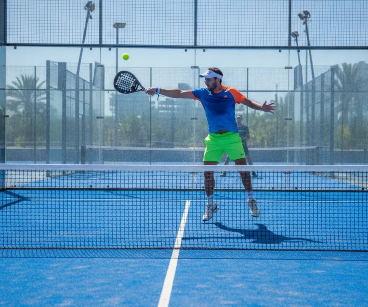 Comparaison padel ou pickleball, joueur de padel en pleine volée sur un court vitré