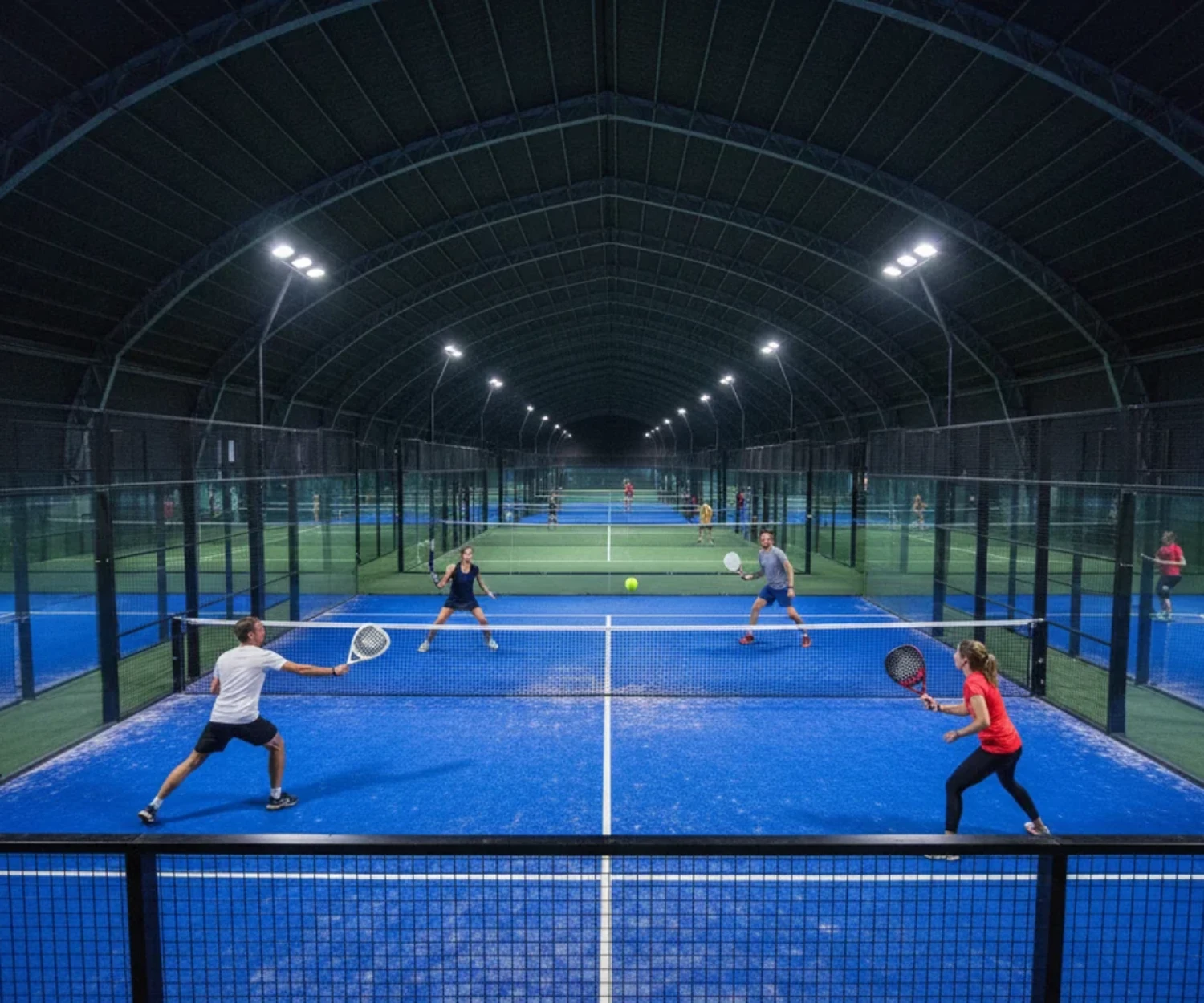 Complexe indoor de padel en Ille-et-Vilaine, plusieurs pistes eclairees et un match de double en cours
