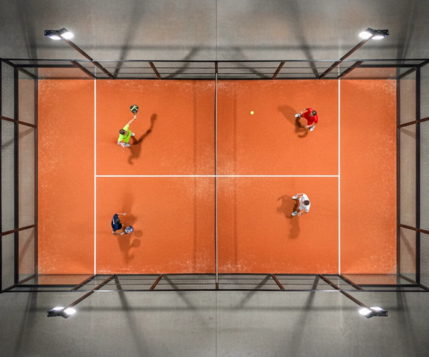 Piste de padel indoor à Rennes vue en plongée, match de double sur gazon orange
