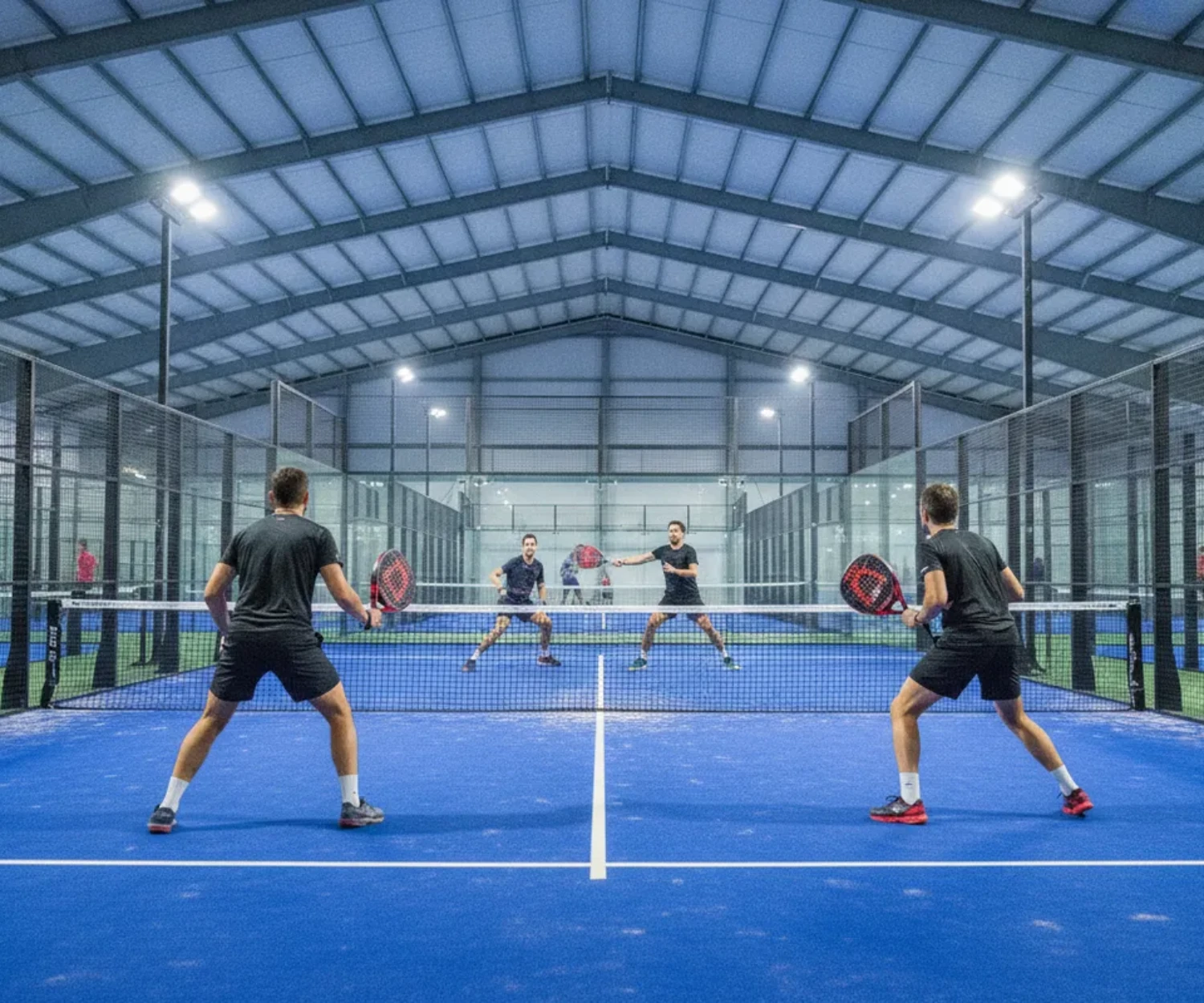 Match de padel en double indoor sur sol bleu, saison couverte par la licence padel FFT