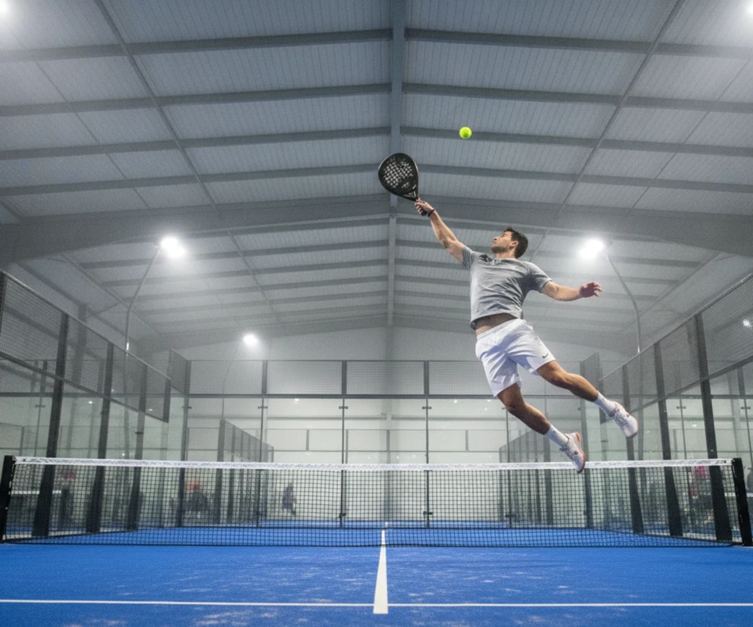 Smash au padel sur une piste indoor bleue, illustration du padel au Mans