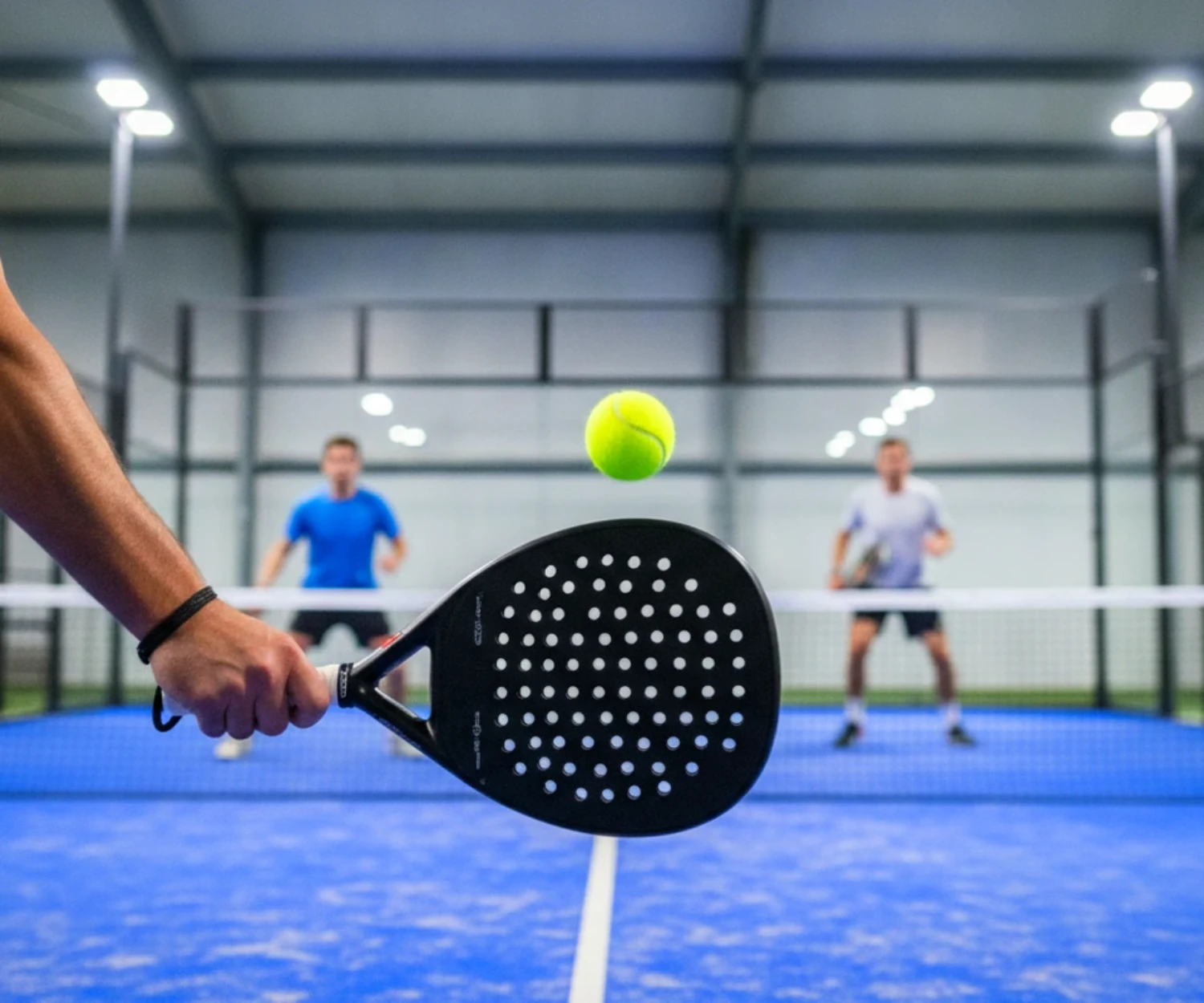 Padel ou pickleball : raquette de padel pleine et perforée face à la balle sur une piste indoor