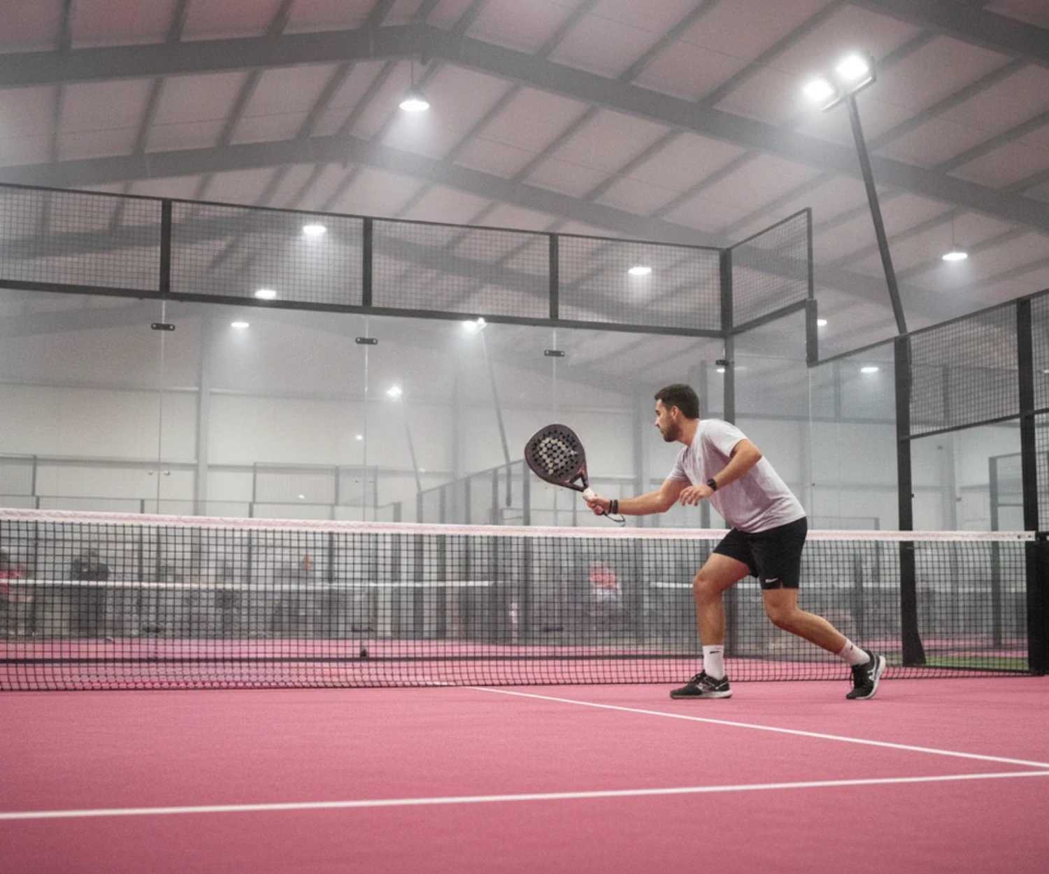 Joueur de padel en préparation de coup droit sur une piste indoor au sol rose, padel à Saint-Brieuc