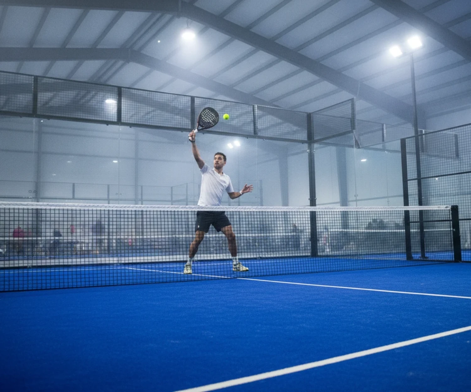 Joueur de padel frappant une bandeja sur un court indoor bleu