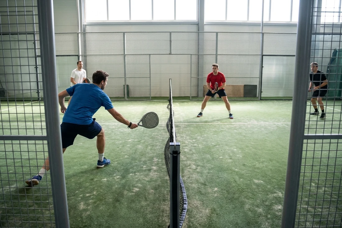 Joueur de padel en fente basse pour une volée près du filet pendant une partie en double sur un sol vert