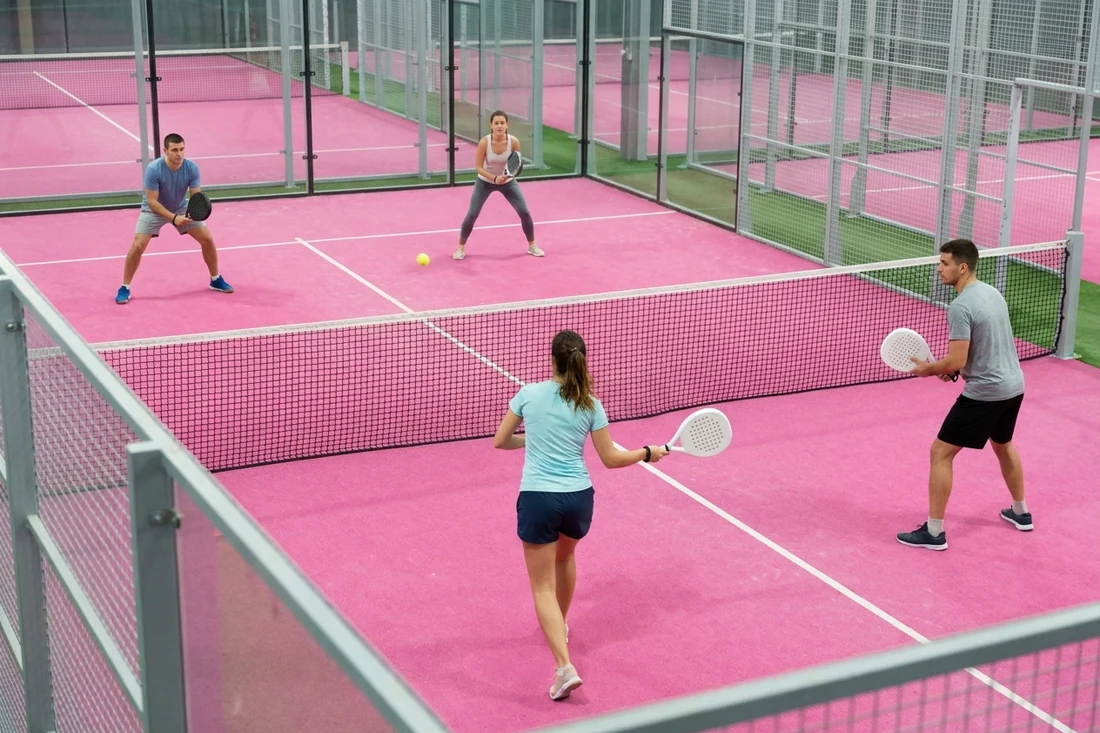 Partie de padel en double entre débutants vue d'en haut sur une piste indoor rose