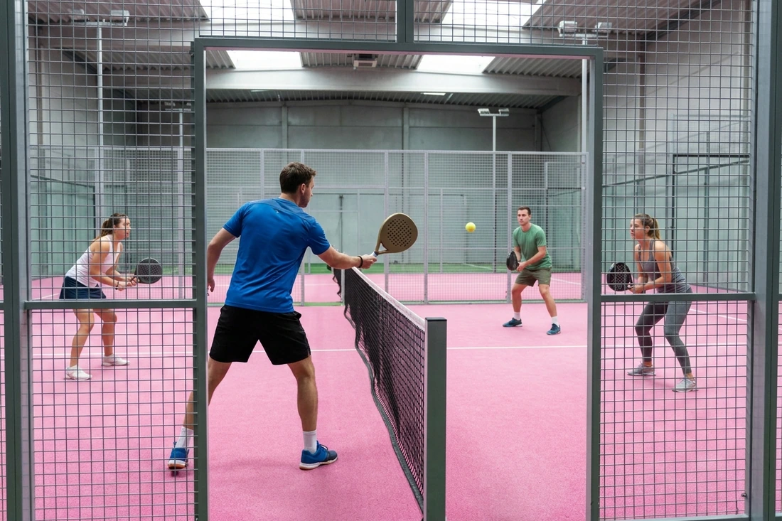 Partie de padel en double entre nouveaux partenaires sur une piste indoor au sol rose, trouver un partenaire de padel à Nantes