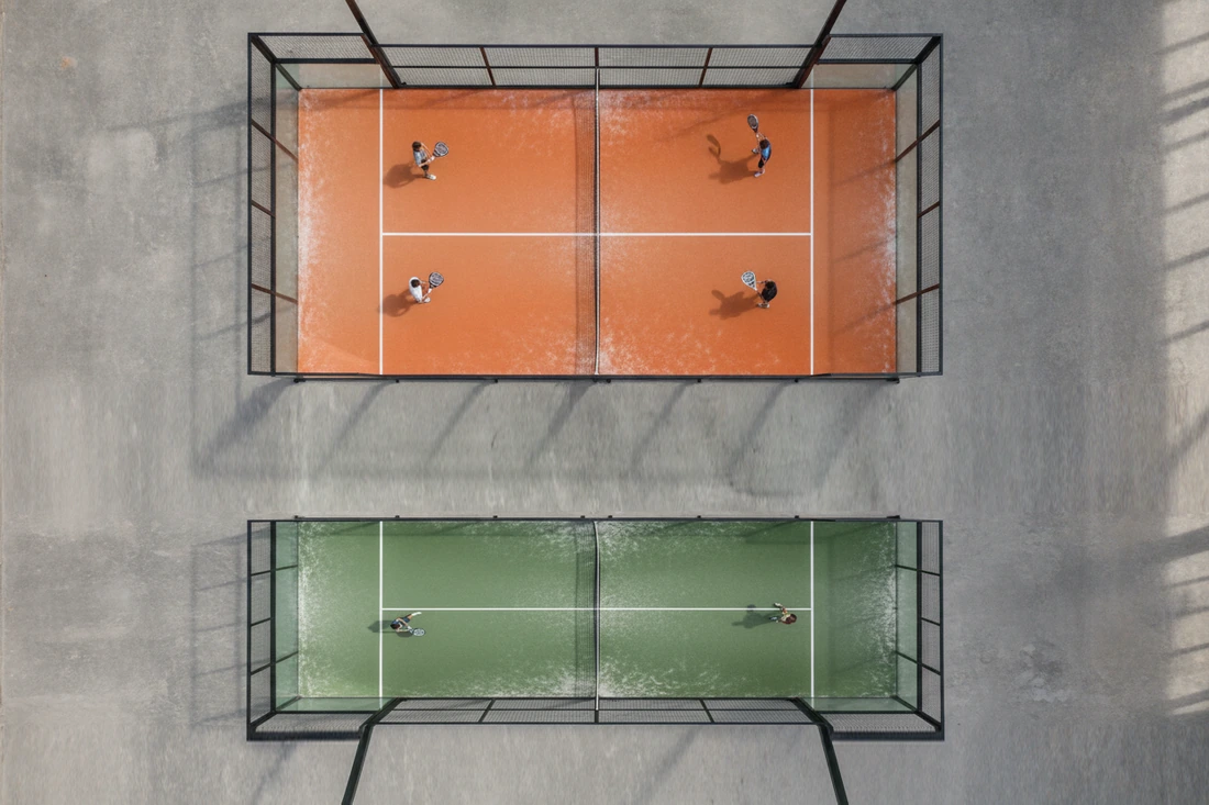 Vue du plafond d'une piste de padel en double à quatre joueurs et d'une piste de simple plus étroite à deux joueurs